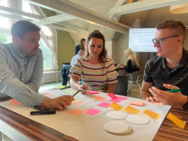 Drie artsen aan tafel met post its aan het overleggen