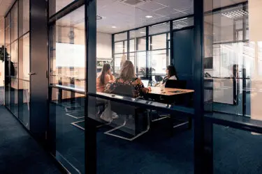 Afbeelding van collega's in een meeting aan tafel in de vergaderzaal aquarium met beeldscherm aan.