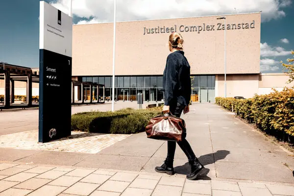 Afbeelding van huisarts die buiten het Jusititeel complex Zaanstad richting de ingang loopt.
