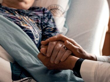 Foto van twee handen die één hand in het midden nemen ter geruststelling