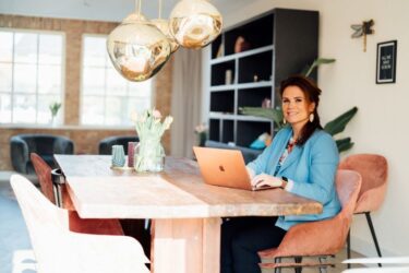 leefstijl coach chantalle bburgers zit aan een tafel met een laptop