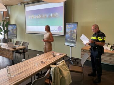 Docent scholing arrestantenzorg geeft presentatie samen met politieagent.