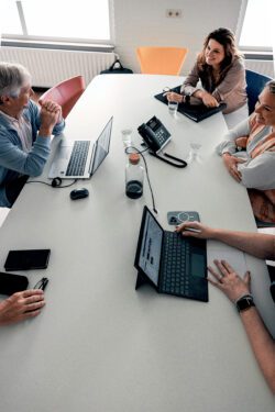 Aan een vergadertafel zitten artsen en zorgprofessionals van een instelling in overleg.
