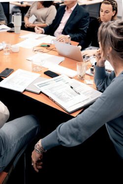 Vergadertafel met veel collega's van medTzorg in vergadering.