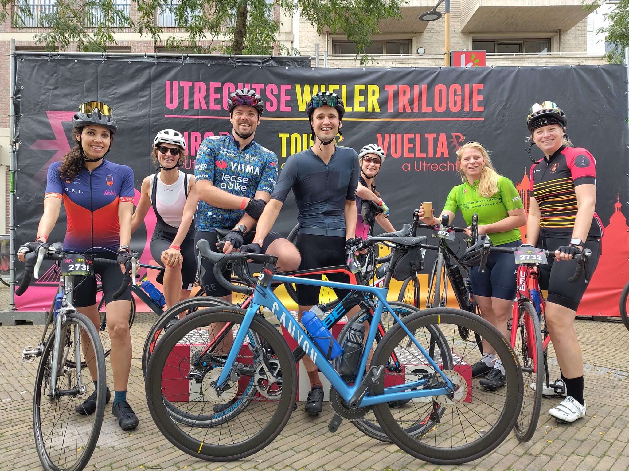 Zeven medTzorg-collega's met hun fietsen poseren aan de start van de Vuelta a Utrecht