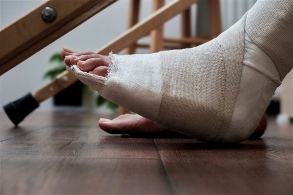 Afbeelding van een voet in het gips met op de achtergrond een loopstok