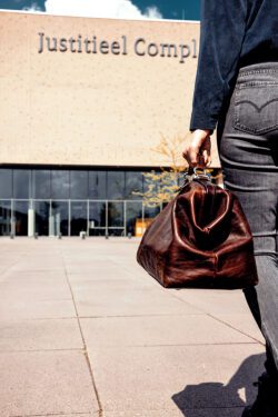 Foto van huisarts die buiten richting het justitieel complex loopt met dokterskoffer in de hand