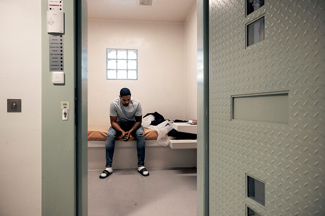 gedetineerde zit op bed in zijn cel
