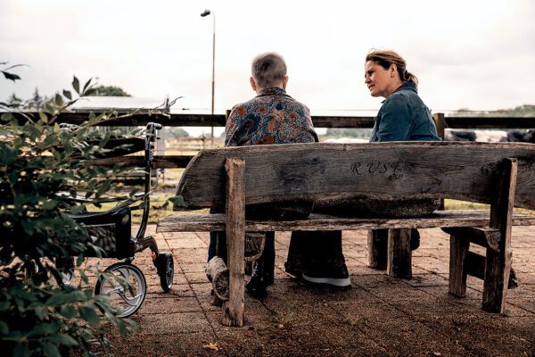 arts in gesprek met oudere op een bankje in de natuur