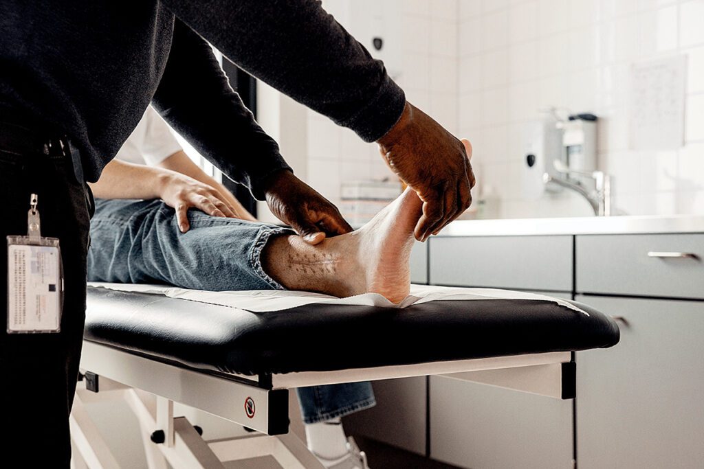 Foto van forensisch arts die patient aan de voet onderzoekt