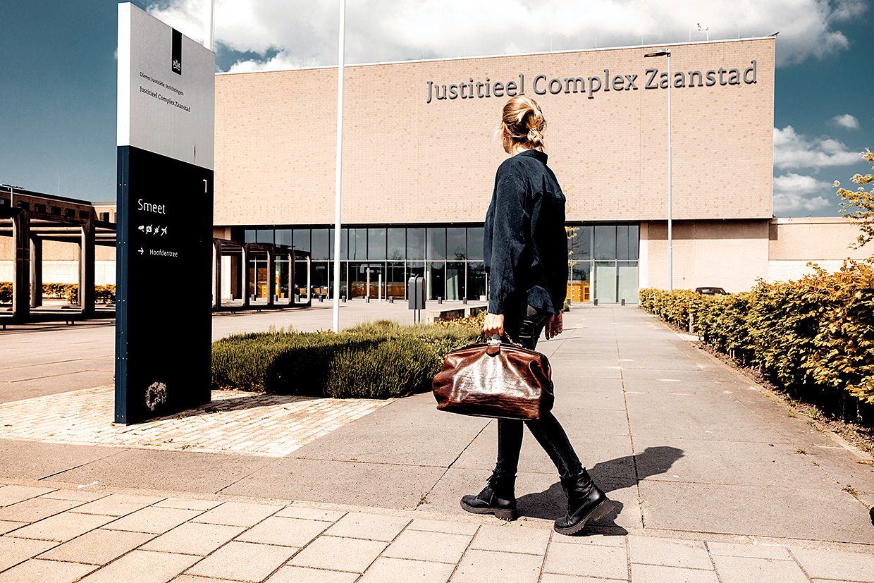 Afbeelding van huisarts die buiten het Jusititeel complex Zaanstad richting de ingang loopt.