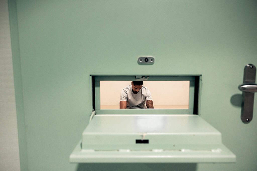 Foto van arrestant in cell gezien door het luikje van de deur