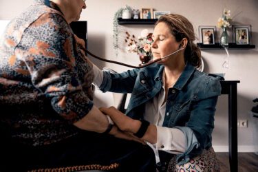 Afbeelding van huisarts die een oudere dame met stethoscoop onderzoekt